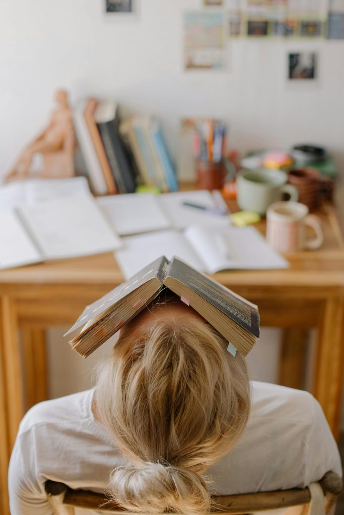 estudiante con un libro encima tratando de dormir en una silla
