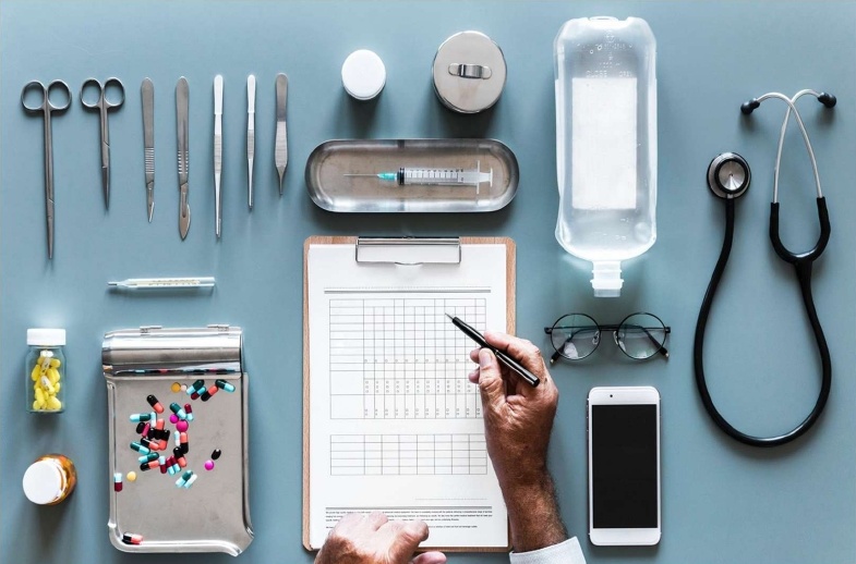 imagen que muestra diversos instrumental médico en un fondo azul con una mano tomando nota formulario de gastos médicos