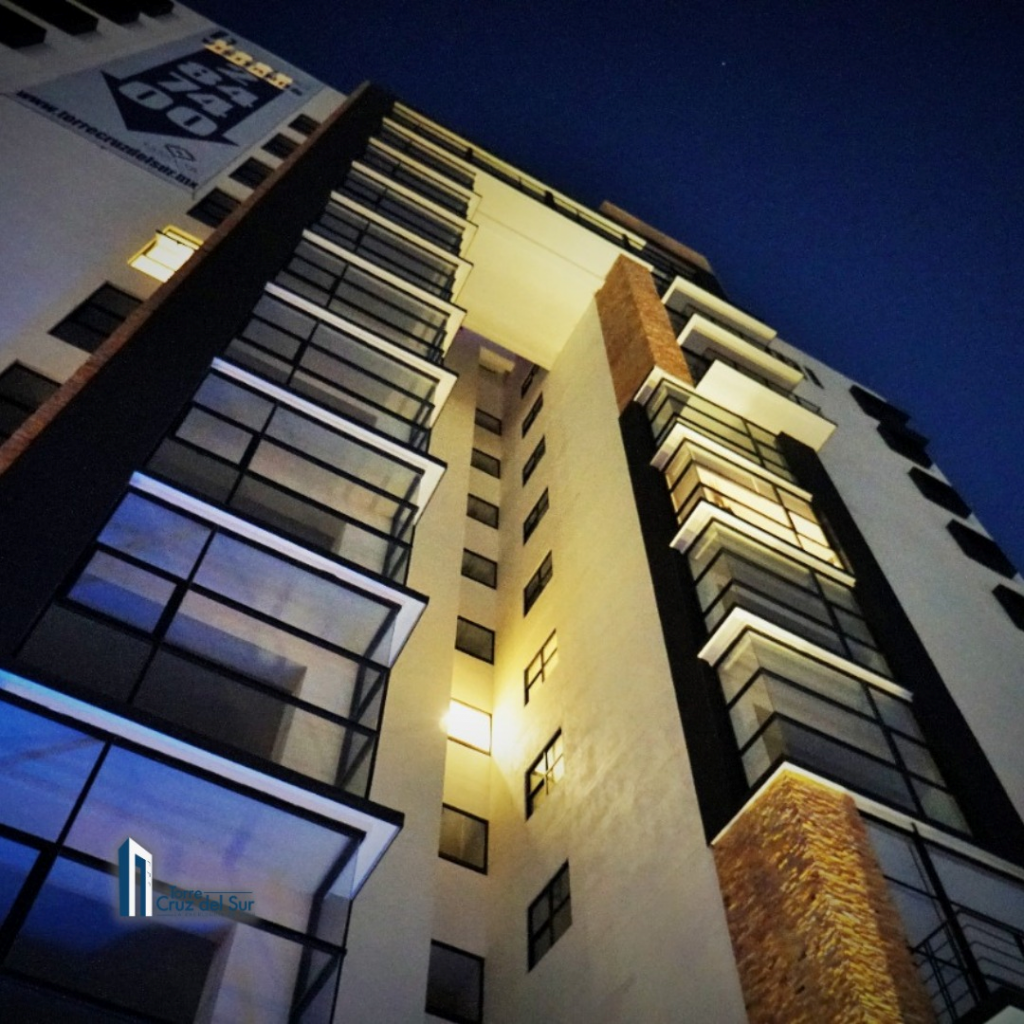 edificio de departamentos con vista desde el acceso principal, al inicio de noche.