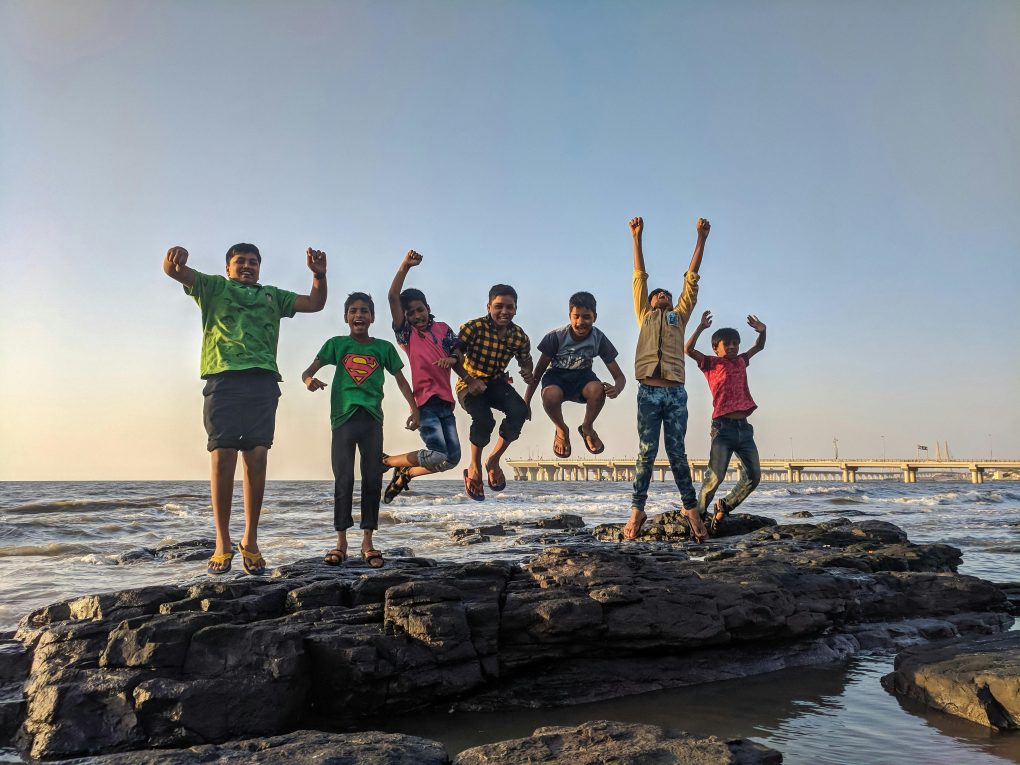 niños felices saltando desde unas rocas en un atardecer en las orillas de una playa, seguro de accidente escolar